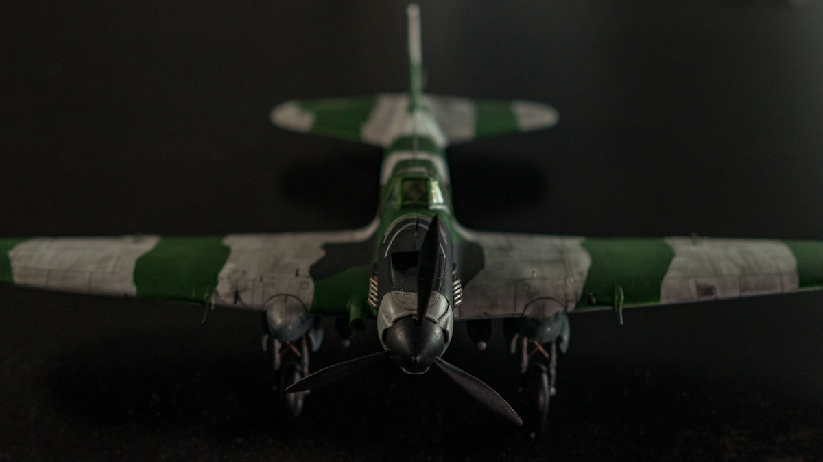 a green and white model airplane on a black surface