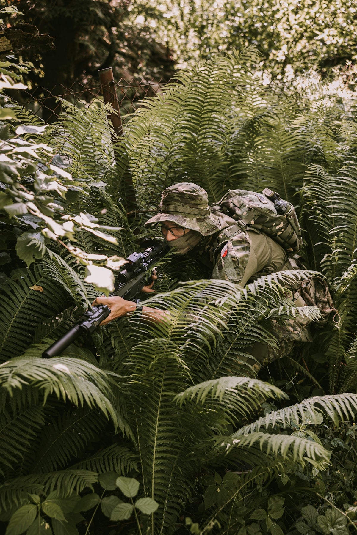 A soldier camouflages in dense foliage.